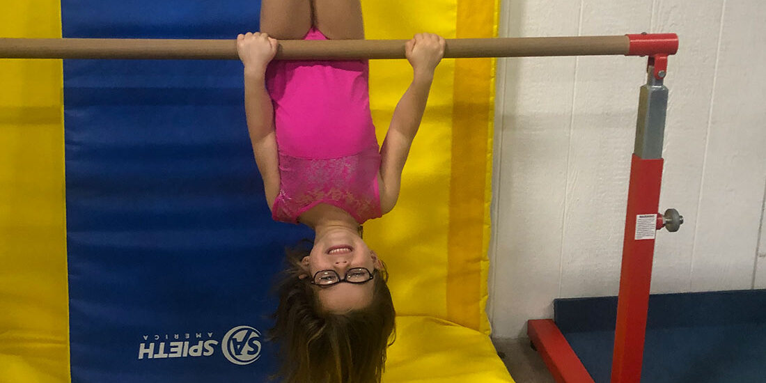 young gymnast hanging upside down