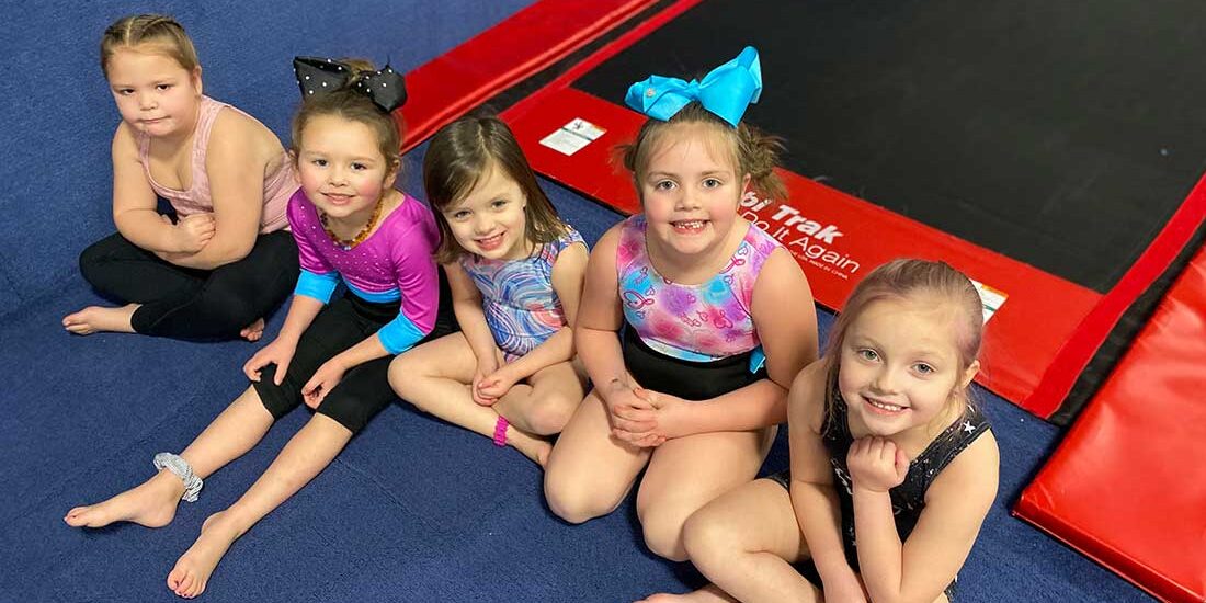 young gymnasts sitting in front of the tumble track