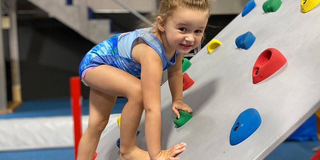 young gymnast climbing and smiling on rock wall